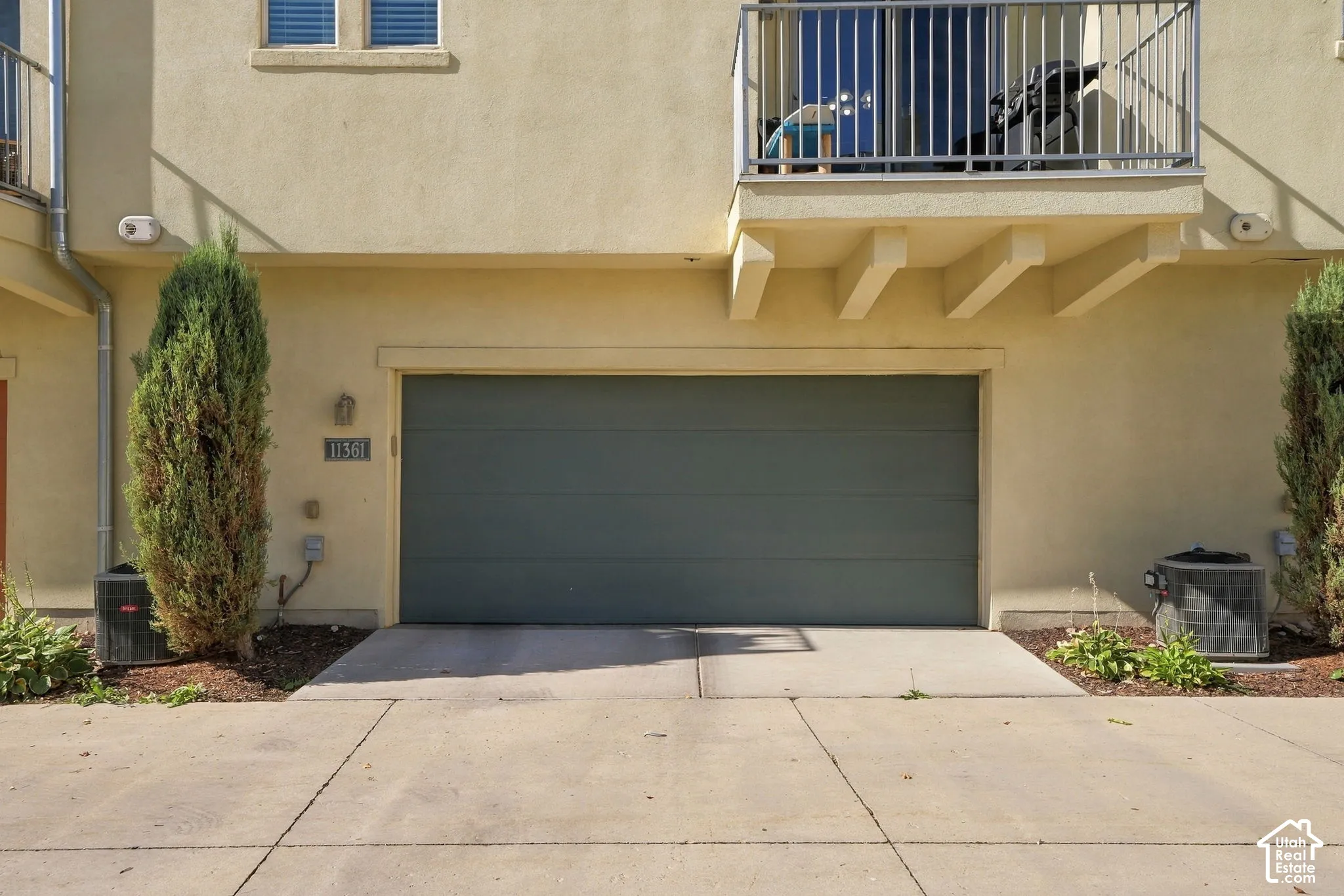 Attached garage with a dark gray door and a private balcony above