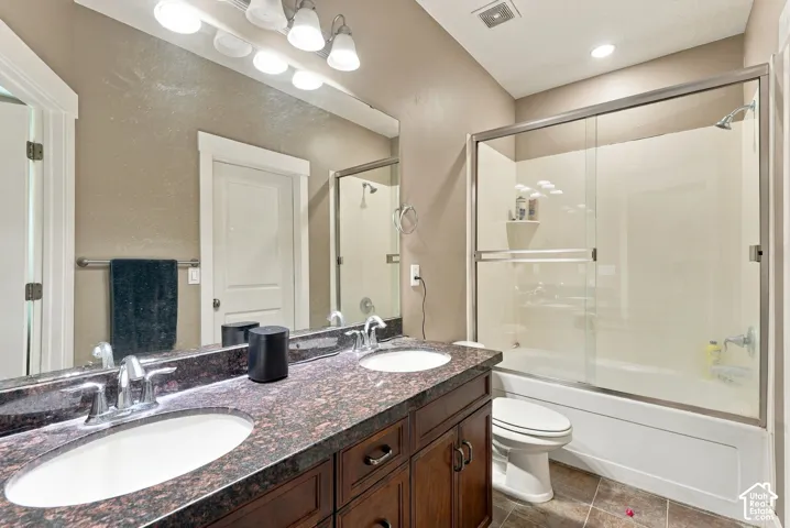 Dual vanity with undermount sinks, stone-finish countertop, and dark wood cabinetry