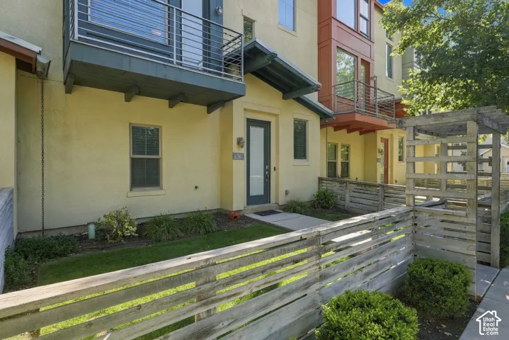Contemporary facade with a wooden privacy fence, front entry, and second-story balcony with metal railing