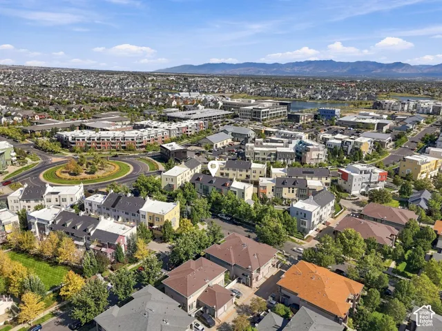 Aerial perspective showcasing a dense residential community with varied architectural styles, mature trees, and mountainous terrain in the distance
