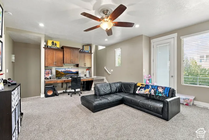 Recessed lighting, ceiling fan with wood-finish blades, and built-in cabinetry with a wood-finish desk area