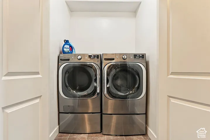 Integrated laundry space with matching front-loading appliances, white paneled doors, and tiled flooring