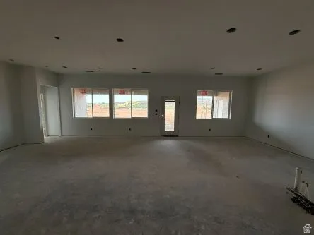 Spacious room with multiple windows, recessed ceiling lighting, and a rear door