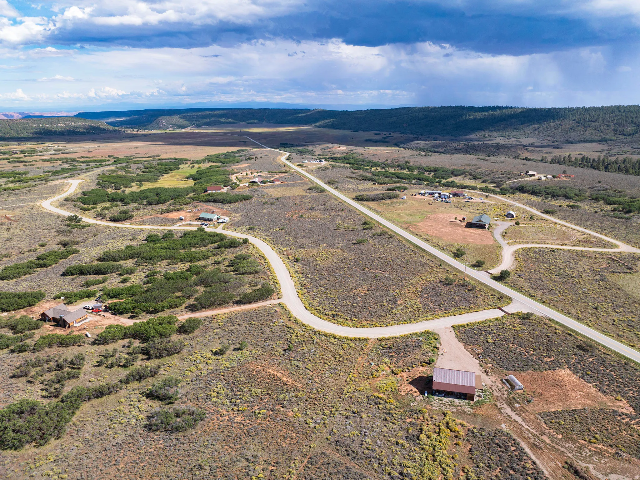 Expansive property featuring a winding road, scattered residences, and distant natural terrain