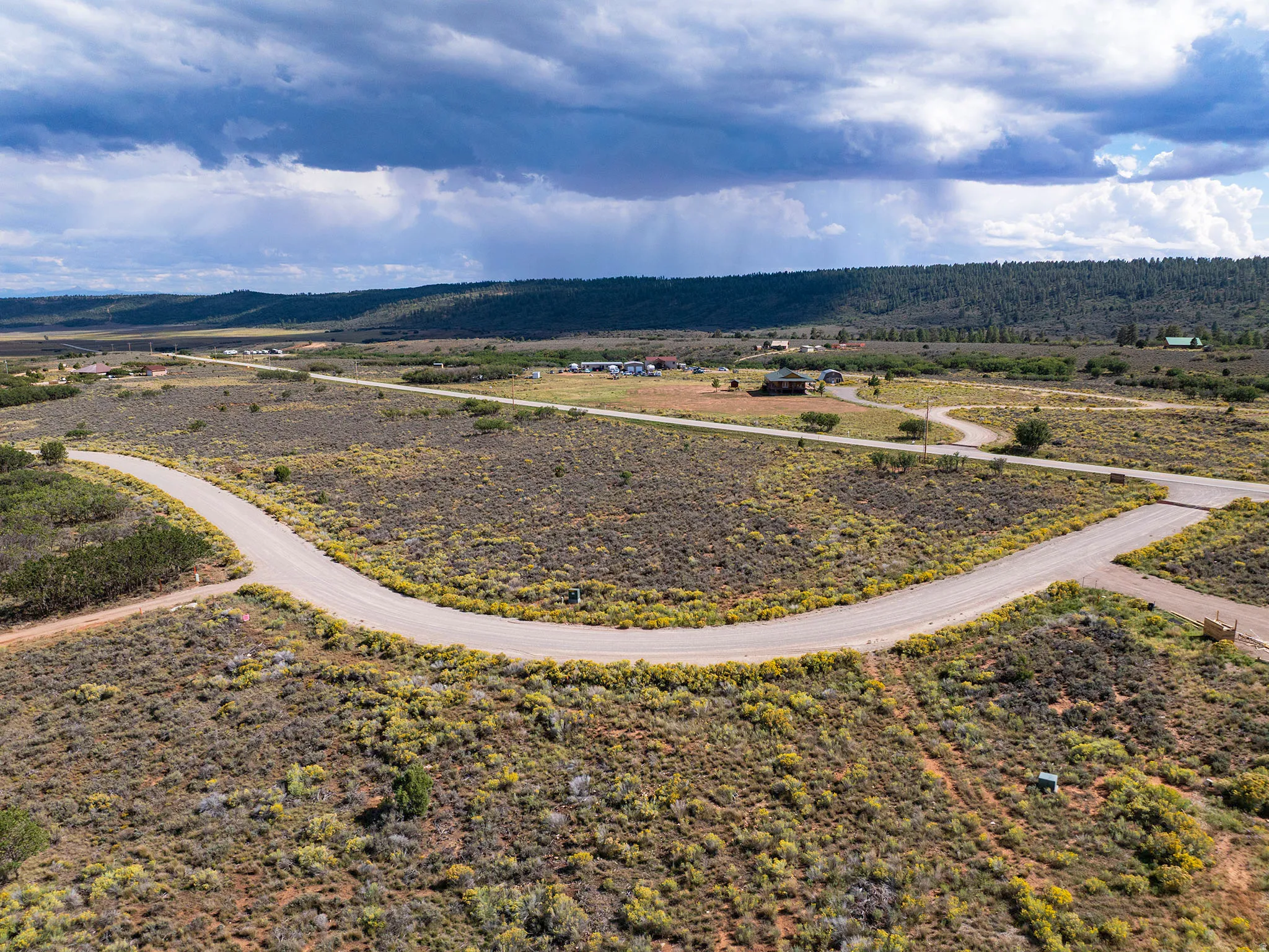 Expansive land parcel featuring a paved road system and established buildings in the distance