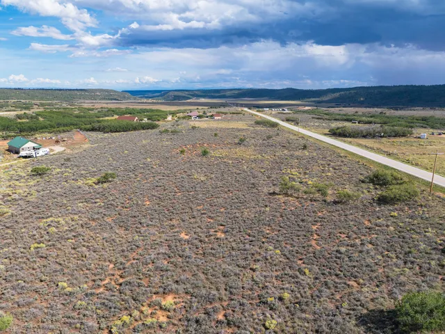 Expansive rural landscape featuring a paved road, scattered structures, and distant natural terrain