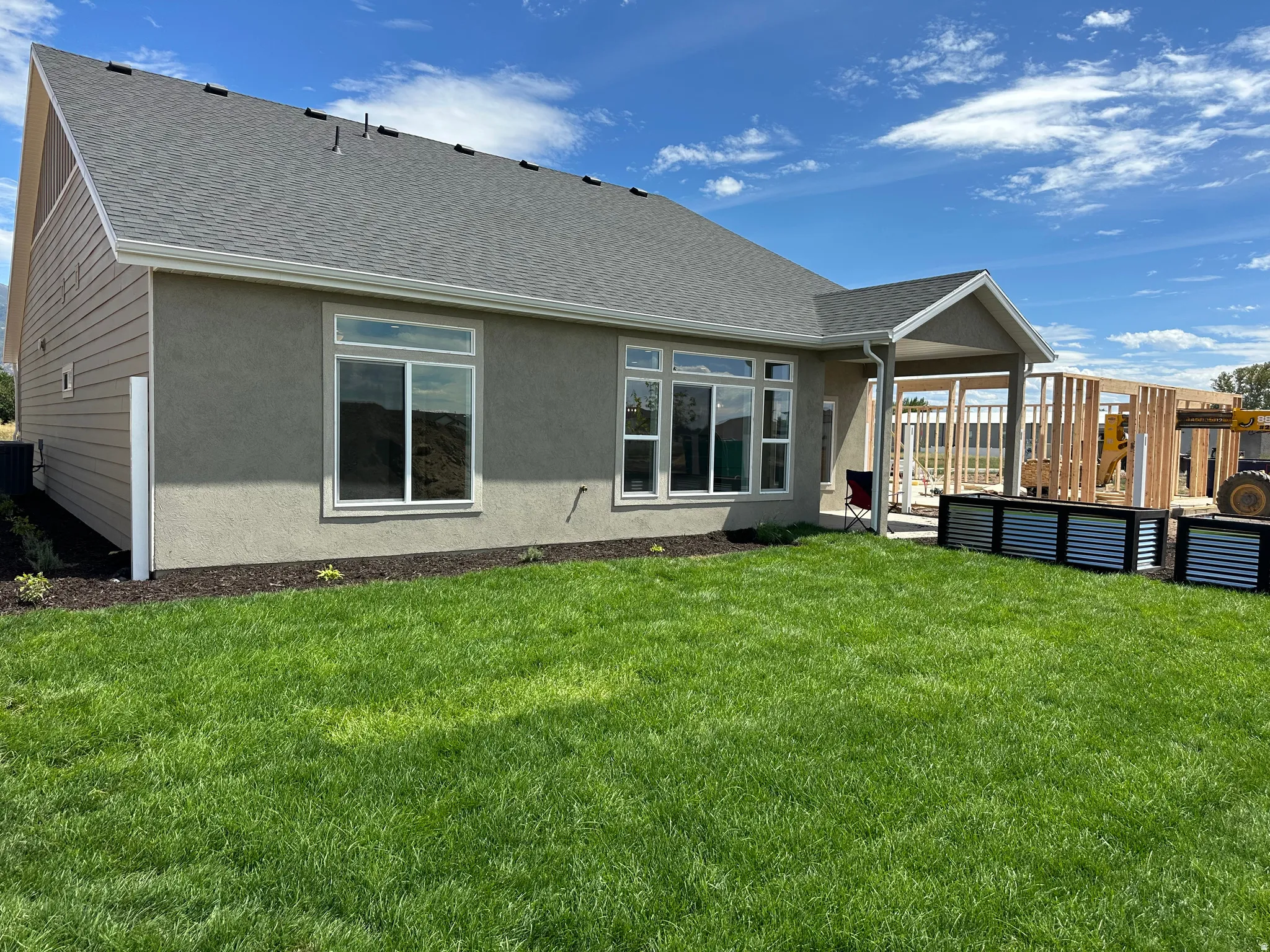 Stucco exterior with a covered patio, multiple windows, and a landscaped perimeter