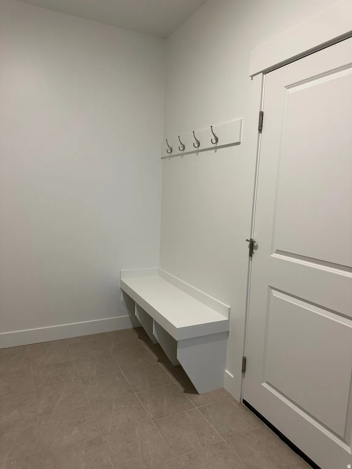 Built-in white bench and wall-mounted coat hooks