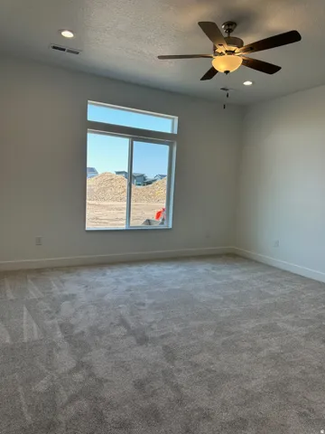 Spacious room featuring a large window with transom, ceiling fan, recessed lighting, and light-toned carpeting