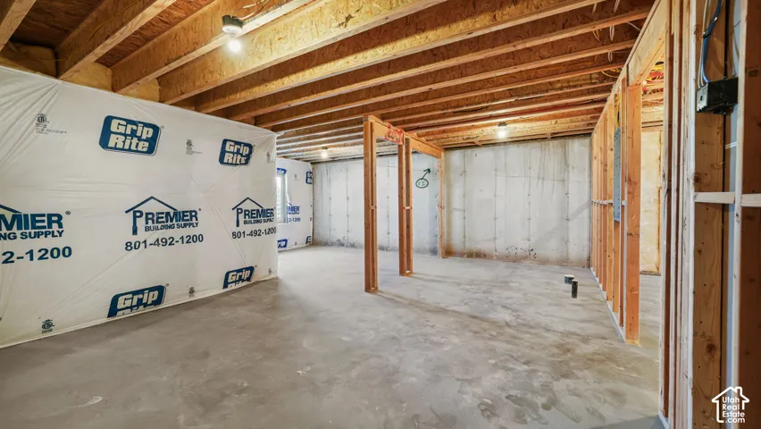 Unfinished basement with exposed wood joists and concrete flooring