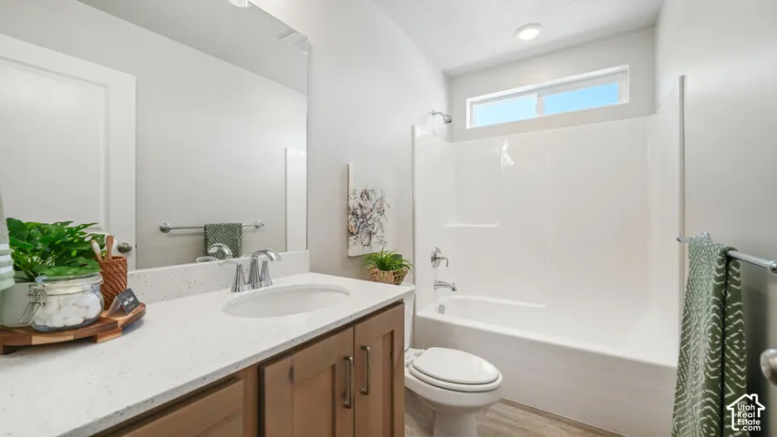 Undermount sink with a chrome faucet, wood-finish vanity with cabinet storage, and a white bathtub with an overhead window