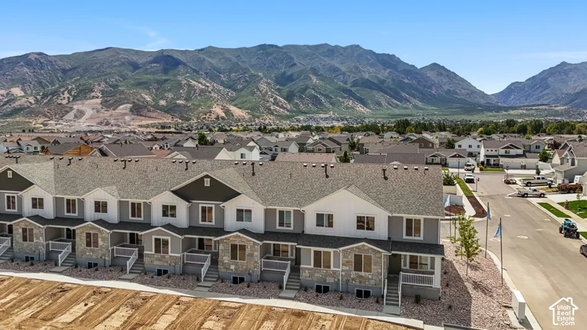 Modern townhome community featuring varied facade finishes, multiple roof lines, and mountain scenery
