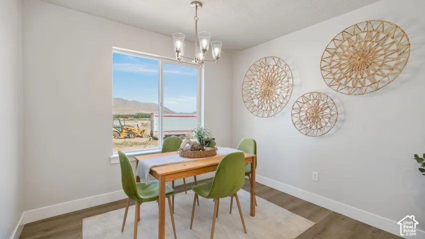 Wood-finish flooring with white baseboards, a large window, and a contemporary chandelier