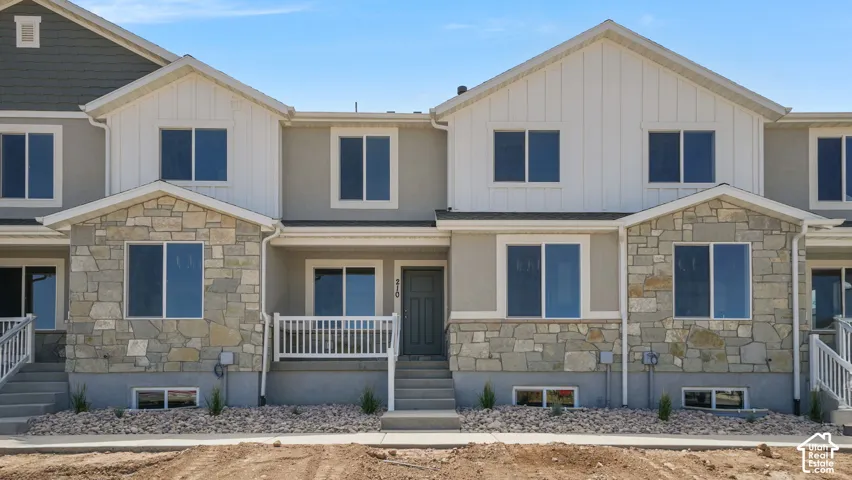 Stone and siding exterior with a covered entry, white porch railings, and a prominent front door