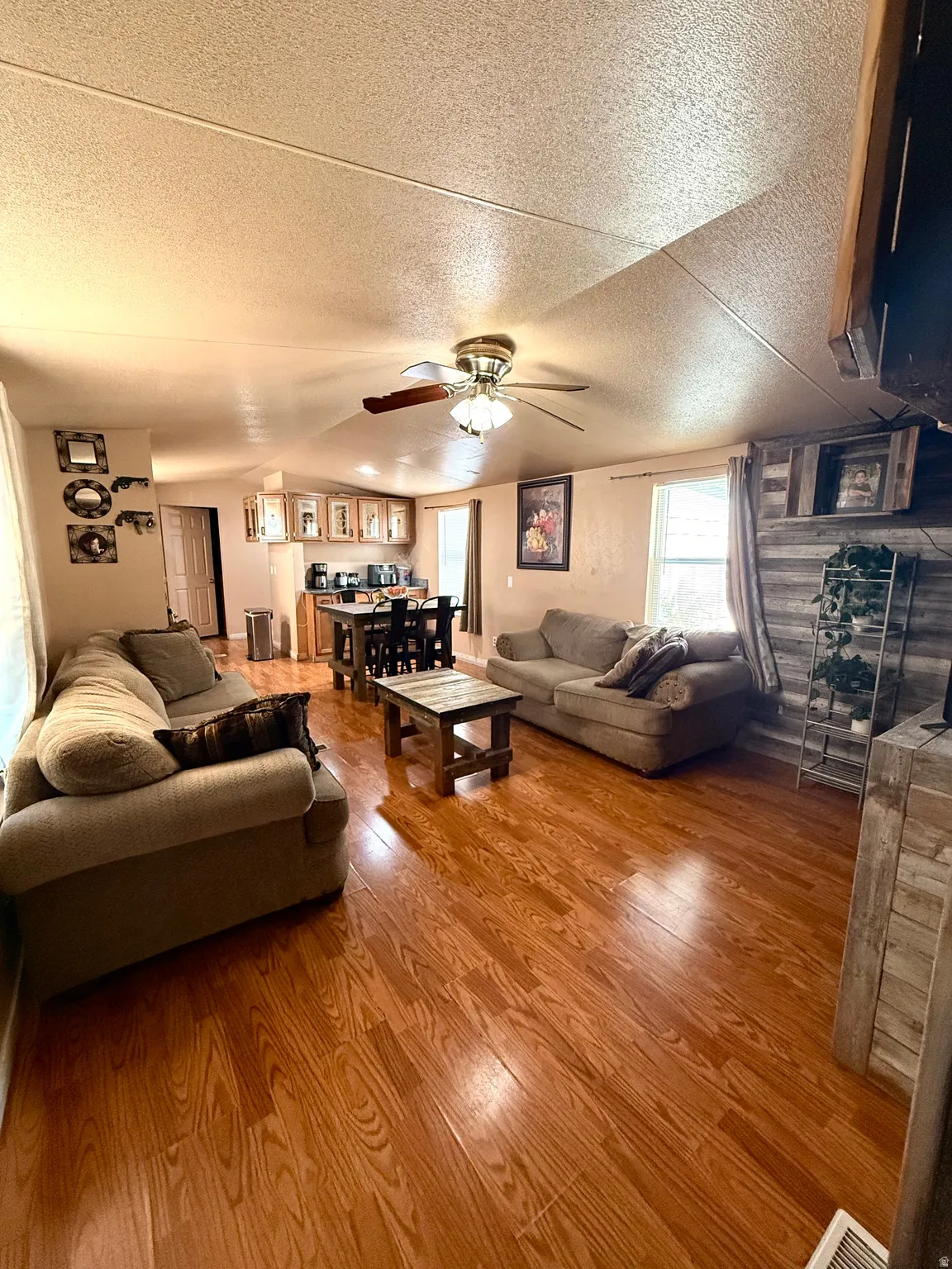 Expansive open-concept living area with wood-finish flooring, recessed lighting, and a ceiling fan