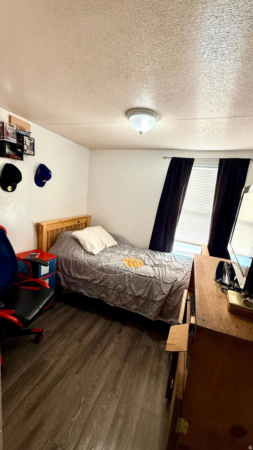 Wood-finish flooring, recessed ceiling lighting, and a window with blinds and dark-toned curtains