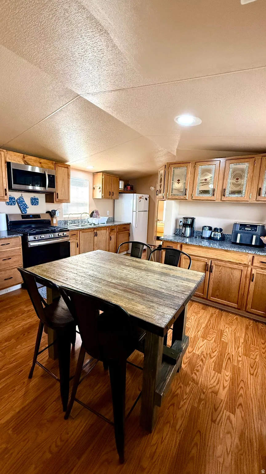 Kitchen featuring wood-finish flooring, recessed lighting, wood cabinetry, and a stainless steel over-range microwave