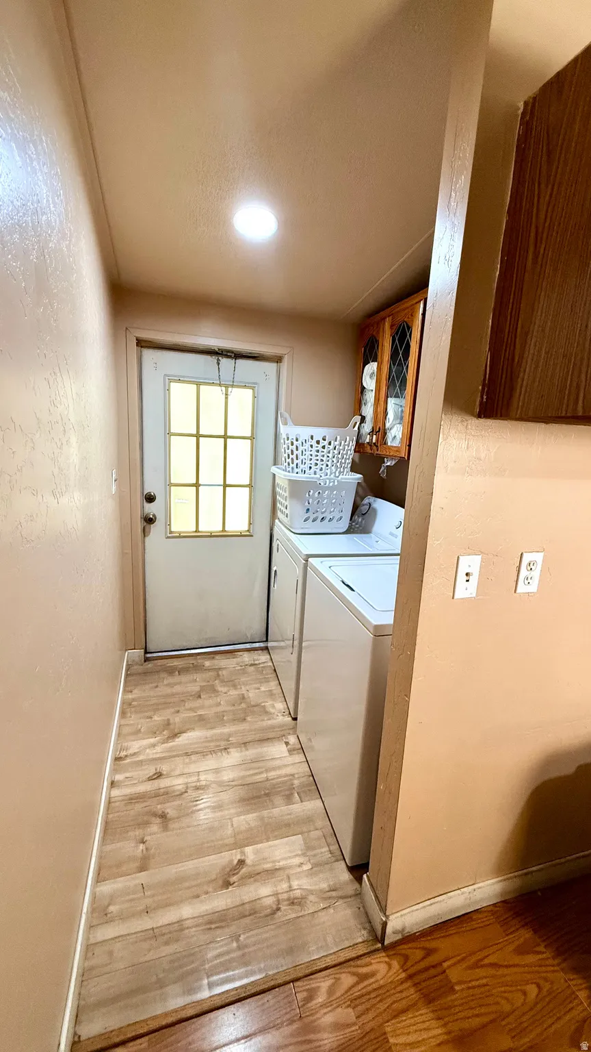 Wood-finish flooring, recessed ceiling light, built-in upper cabinetry, and a grid-paneled door