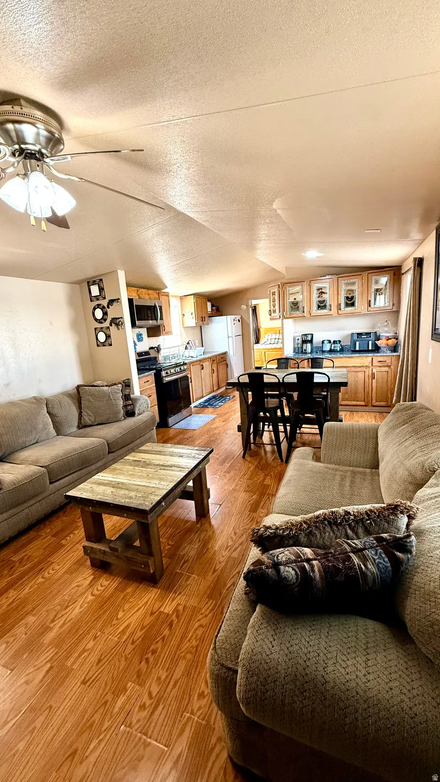 Wood-finish flooring throughout, ceiling fan with light fixture, natural wood cabinetry, and recessed lighting