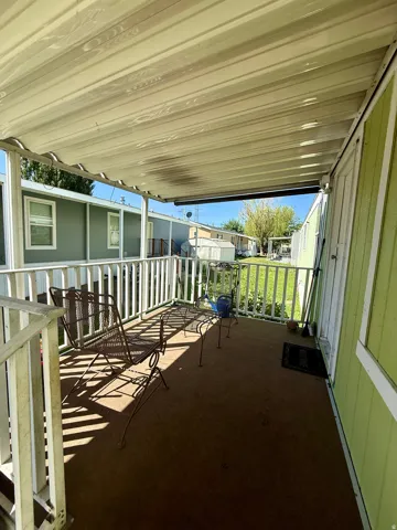 Covered patio with white railing and green siding