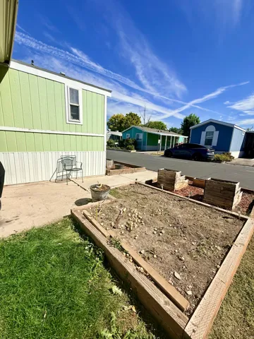 Exterior featuring vinyl siding, single-hung windows, and a raised garden bed