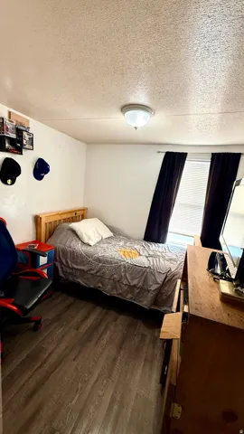 Wood-finish flooring, recessed ceiling lighting, and a window with blinds and dark-toned curtains