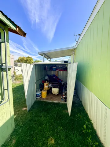 Detached storage shed with a corrugated metal roof and doors