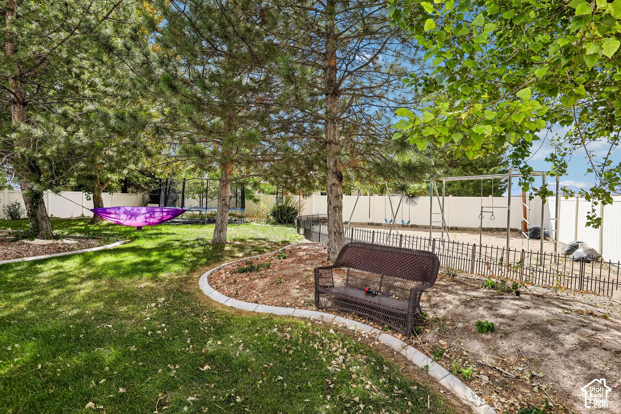 Expansive backyard featuring a manicured lawn, established trees, and a privacy fence