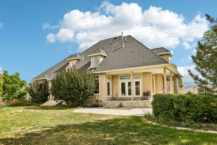 Rear exterior featuring a covered patio, multiple sets of French doors, an asphalt shingle roof, and dormer windows