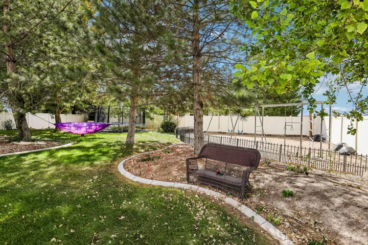 Expansive backyard featuring a manicured lawn, established trees, and a privacy fence