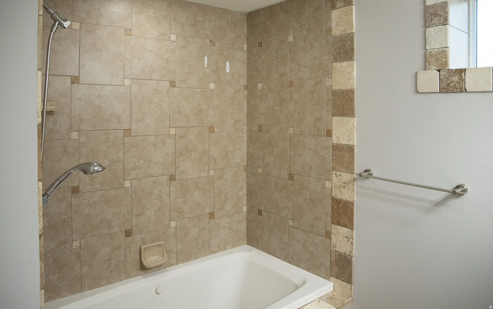 Recessed bathtub with full-height tile surround, accented by smaller square tiles