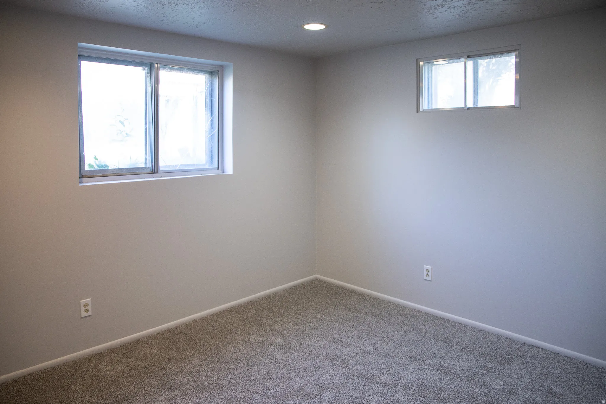 Neutral-toned walls, recessed lighting, and soft gray carpeting provide a versatile interior