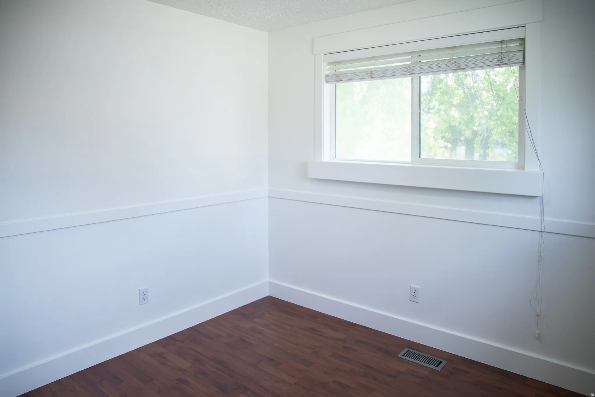 Wood-finish flooring with white baseboards and chair rail molding