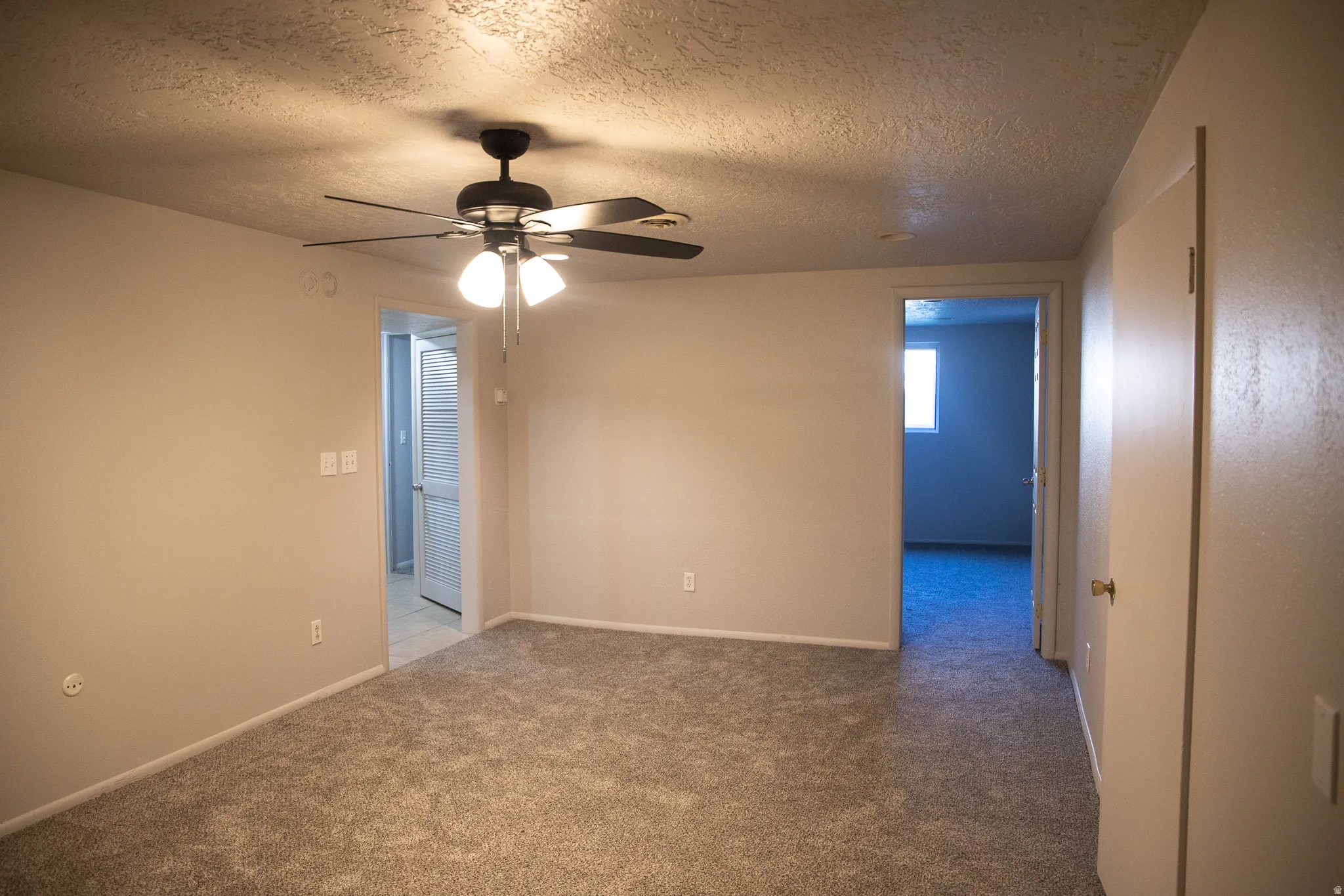 Wall-to-wall carpeting and a ceiling fan with integrated lighting