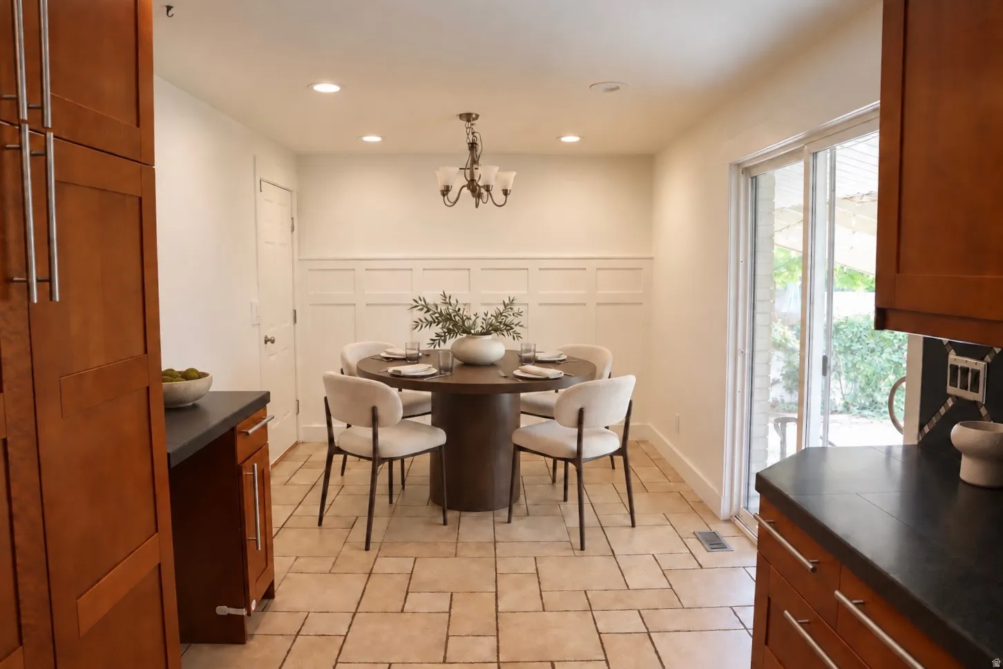 Recessed lighting, warm wood cabinetry, neutral tone tile flooring, board and batten wall detailing, and a sliding glass door