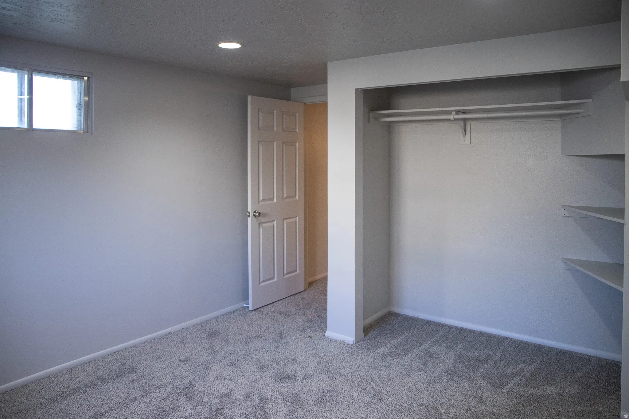 Recessed ceiling lighting, window, paneled interior door, built-in closet shelving, and carpet flooring