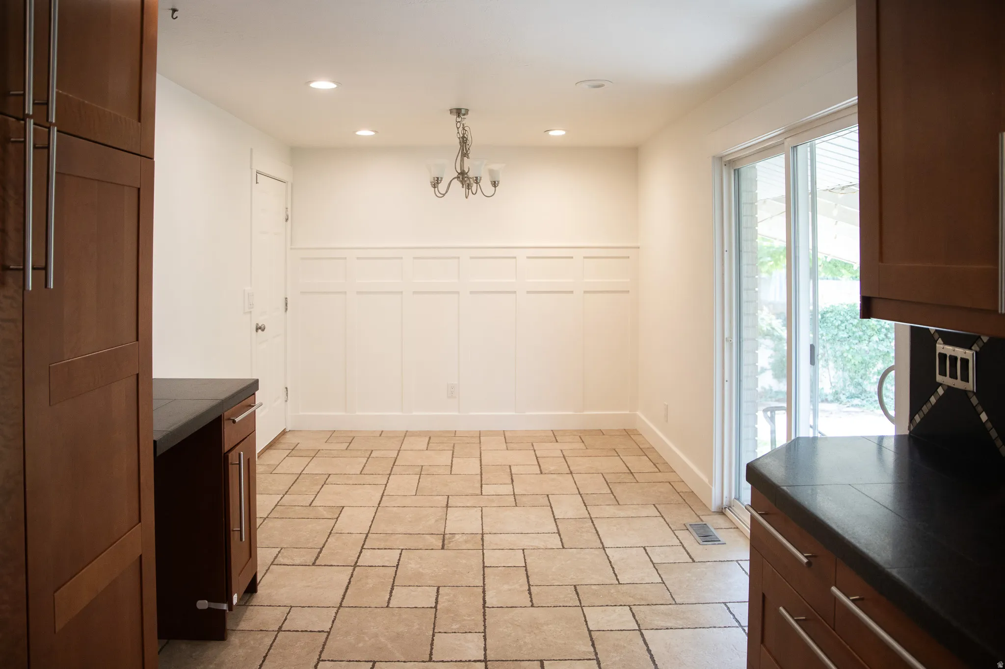 Tile flooring, wainscoting, recessed lighting, sliding glass door, and a decorative chandelier