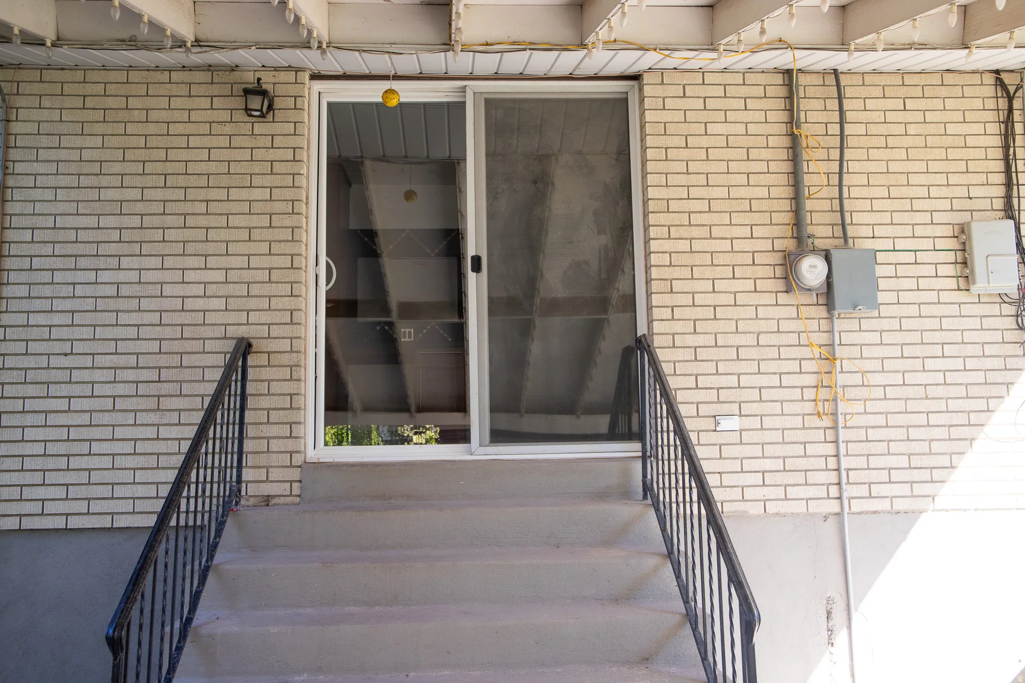 Brick exterior with a security light fixture and white sliding glass door