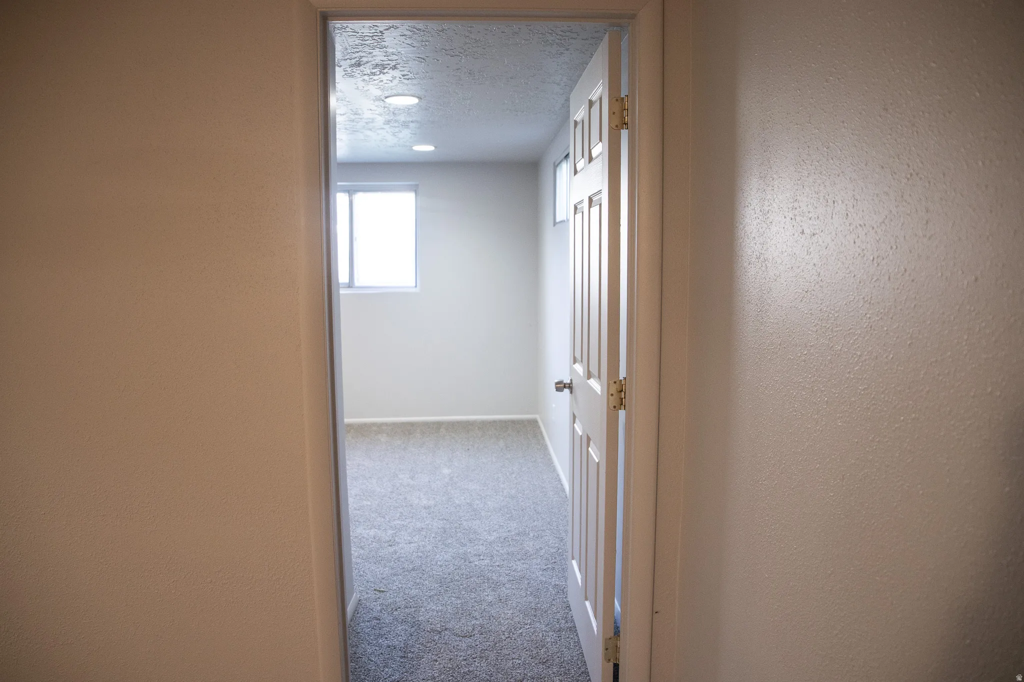 Room featuring neutral-toned carpeting, light-colored walls, recessed lighting, and a window for natural illumination