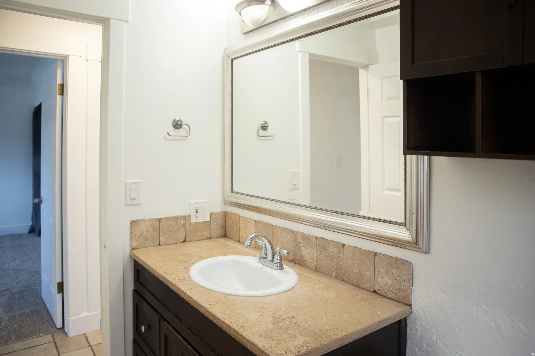 Vanity with integrated sink, stone-finish countertop, and decorative tile backsplash