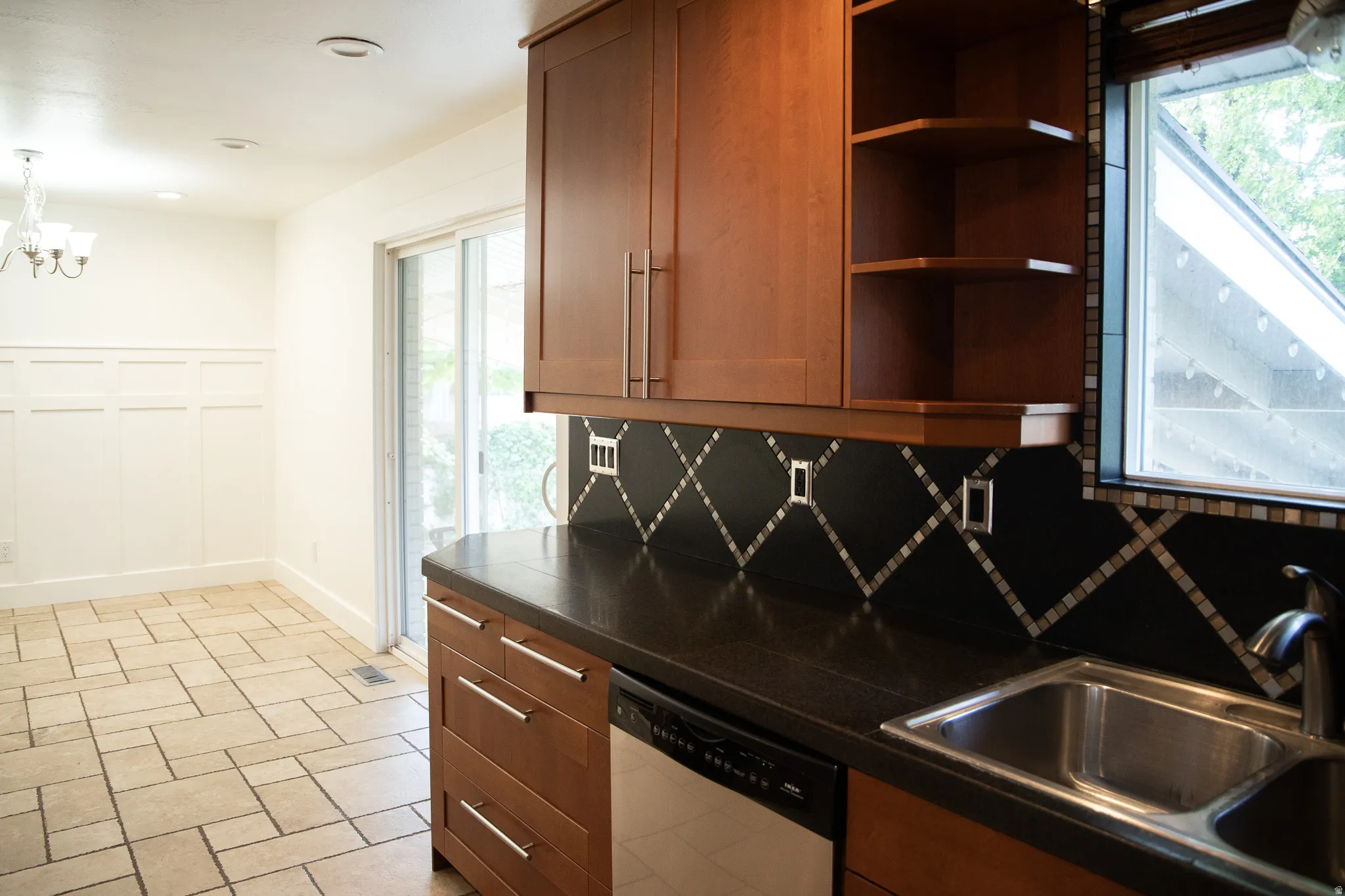 Wood-finish cabinetry with silver-tone hardware, dark countertop, and a stainless steel sink