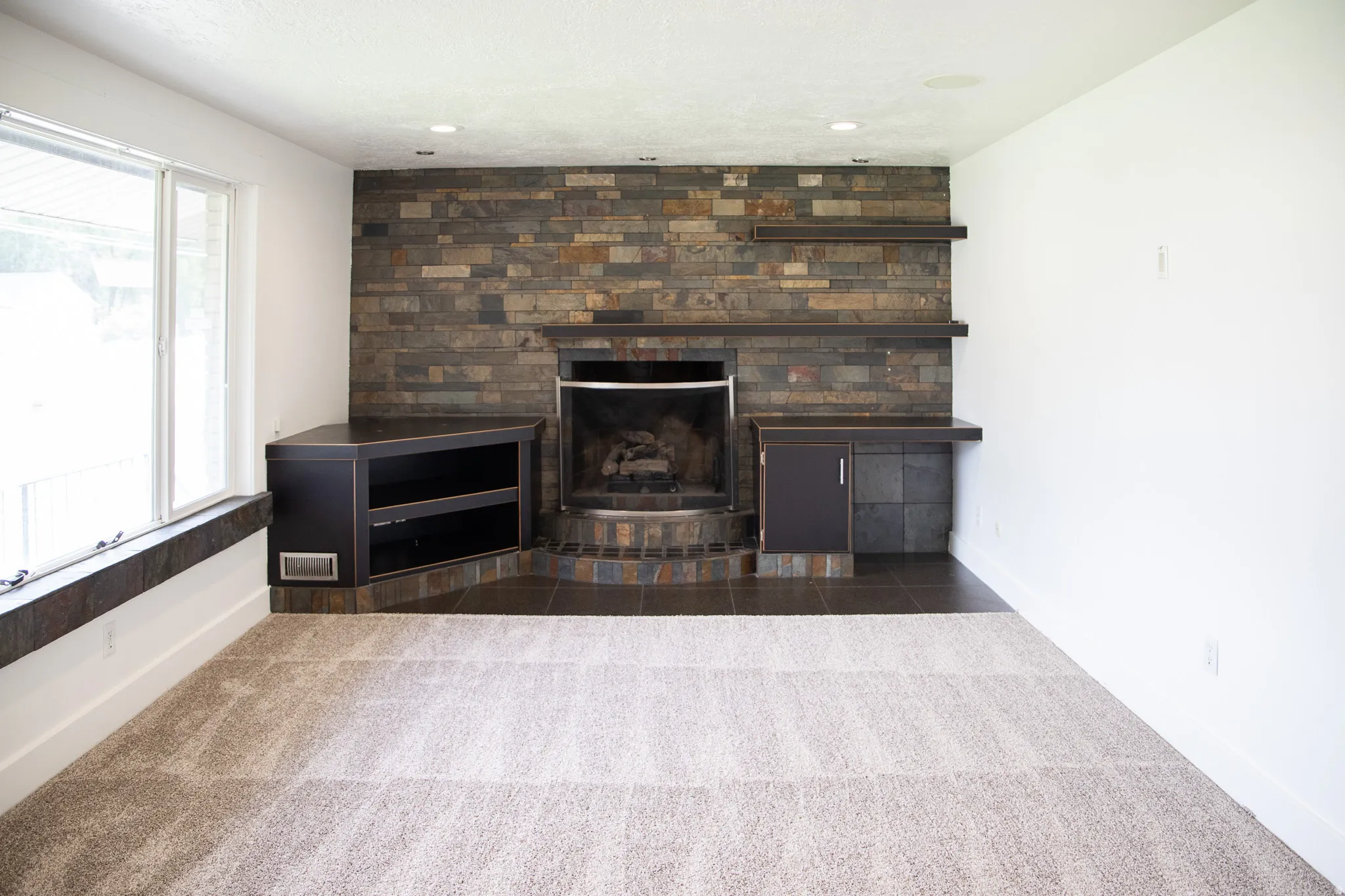 Stacked stone fireplace with a tile hearth and integrated built-in shelving