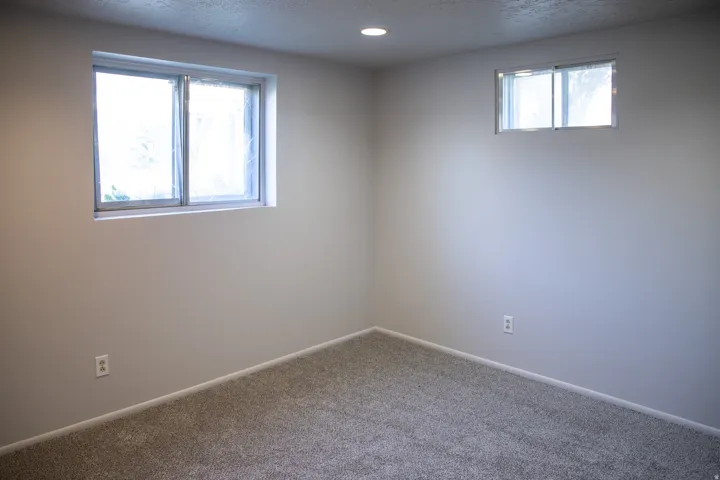 Neutral-toned walls, recessed lighting, and soft gray carpeting provide a versatile interior
