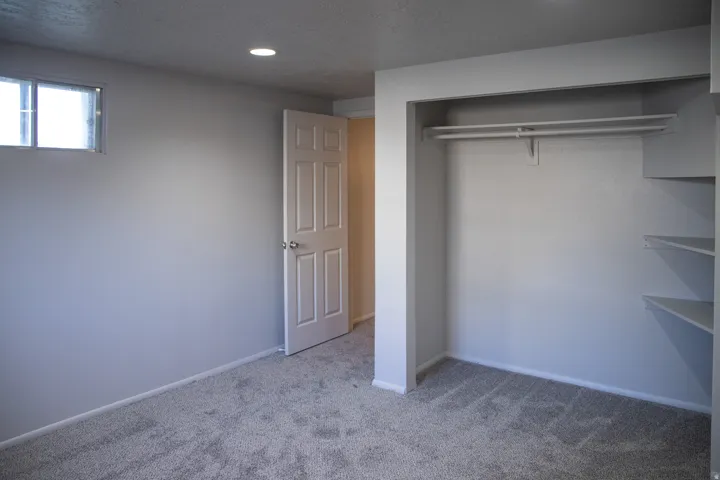 Recessed ceiling lighting, window, paneled interior door, built-in closet shelving, and carpet flooring