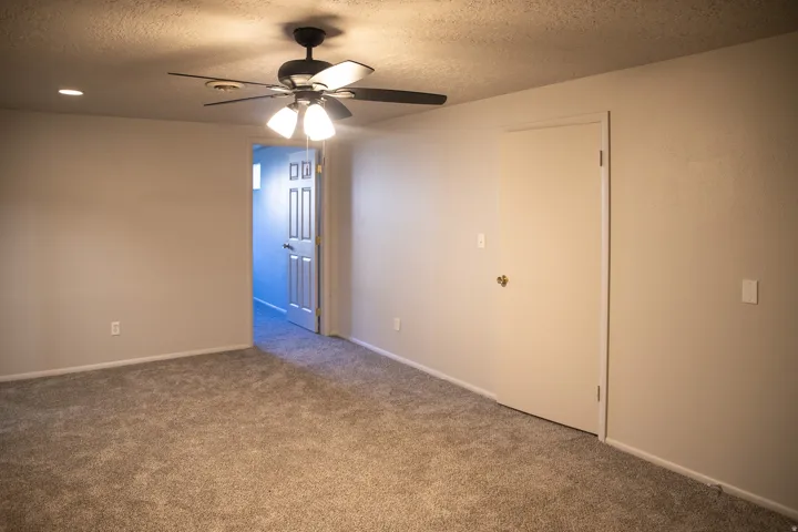 Neutral-toned walls with ceiling fan, recessed lighting, and carpeted flooring