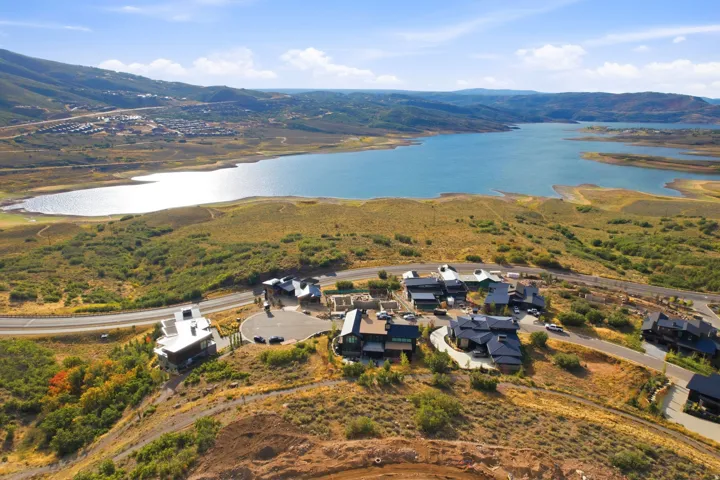 Aerial perspective highlighting multiple properties, a prominent body of water, and surrounding natural terrain