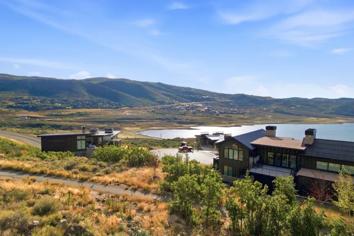 Modern residential architecture with dark exterior cladding and expansive glazing overlooking a pristine alpine lake and mountain landscape