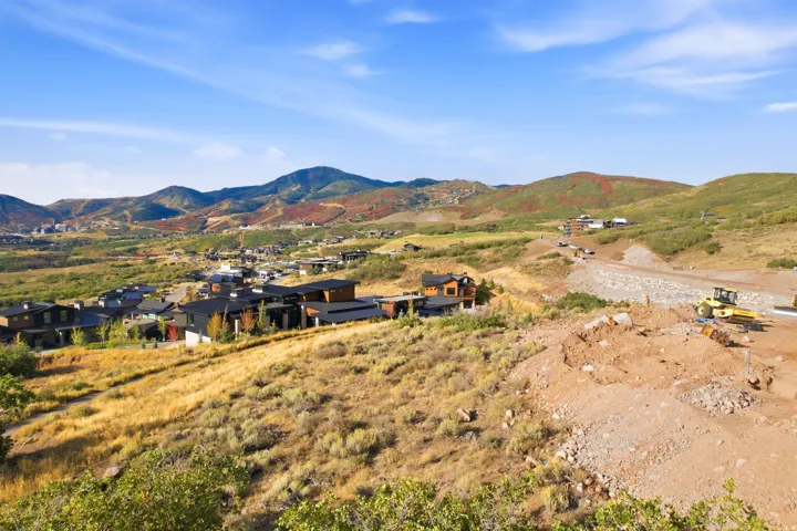 Expansive hillside terrain featuring distant mountain ranges and a developing residential area