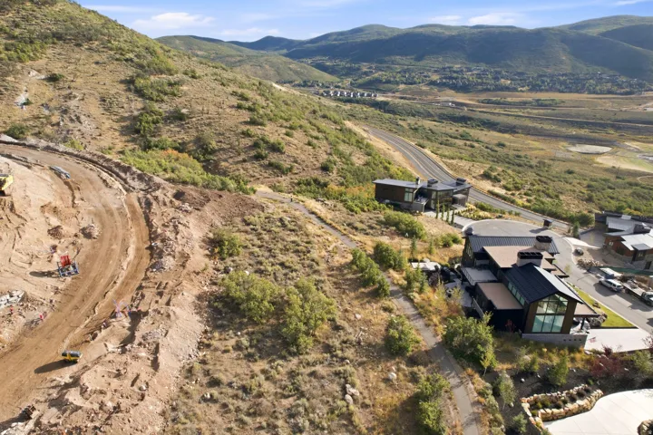 Mountainous terrain with natural vegetation, winding paved road, and modern architectural structures