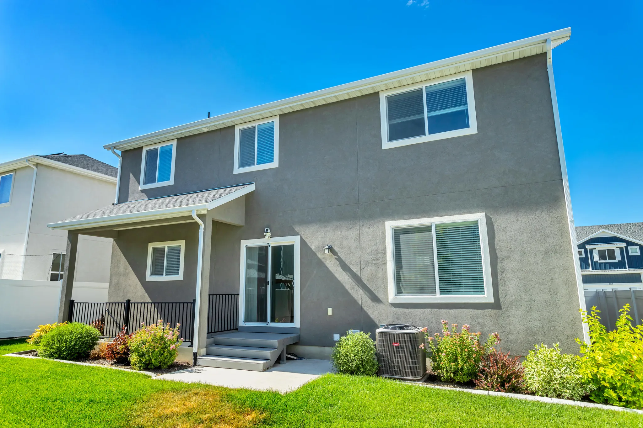 Rear exterior with a covered patio, sliding glass door, and a manicured lawn